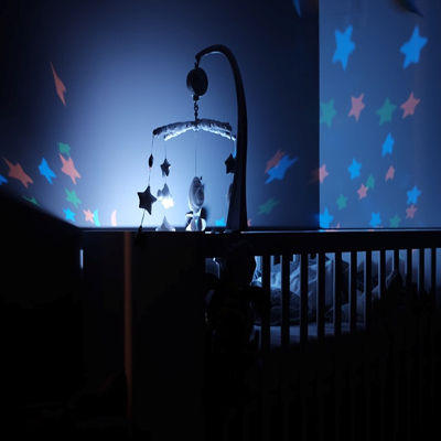 A crib lit by a hanging mobile