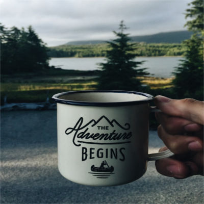 A coffee cup that says "The Adventure Begins"