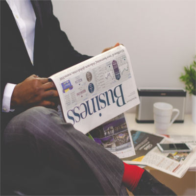 A man in a suit reading the business section of the newspaper