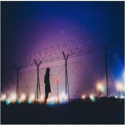 A person standing outside a person fence at night