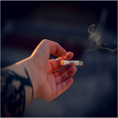 A person holding a lit cigarette